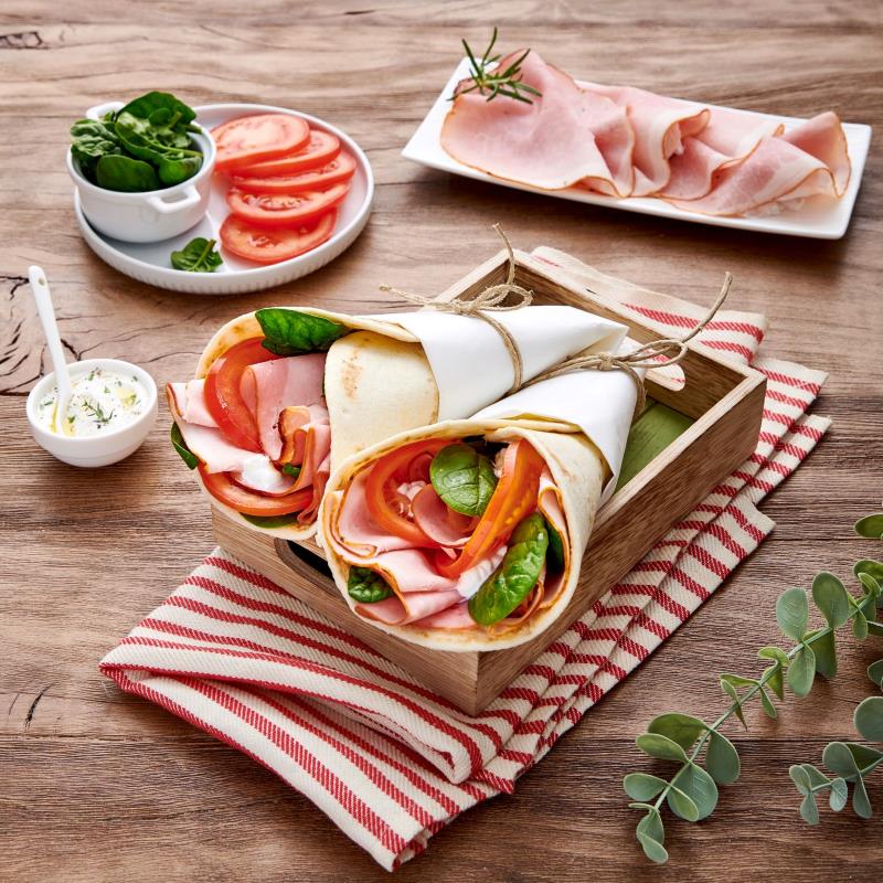 Gefüllter Loriana Piadina ARROTOLABILE OLIO Wrap mit Schinken und Tomaten auf einem Tisch, bereit zum Genießen. Authentische italienische Küche.