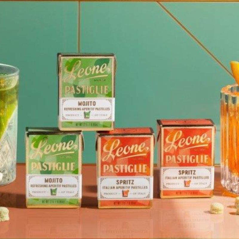 Zwei Verpackungen Leone Pastillen Mojito gestapelt neben zwei Verpackungen Leone Spritz Pastillen auf einem grünem Hintergrund. Ideal für erfrischende Genussmomente.